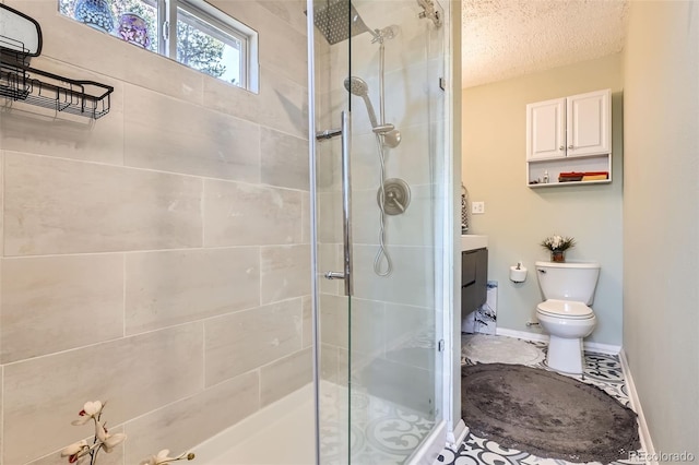 bathroom featuring a stall shower, toilet, a textured ceiling, baseboards, and vanity