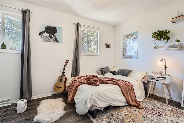 bedroom with a textured ceiling, visible vents, and dark wood-style floors