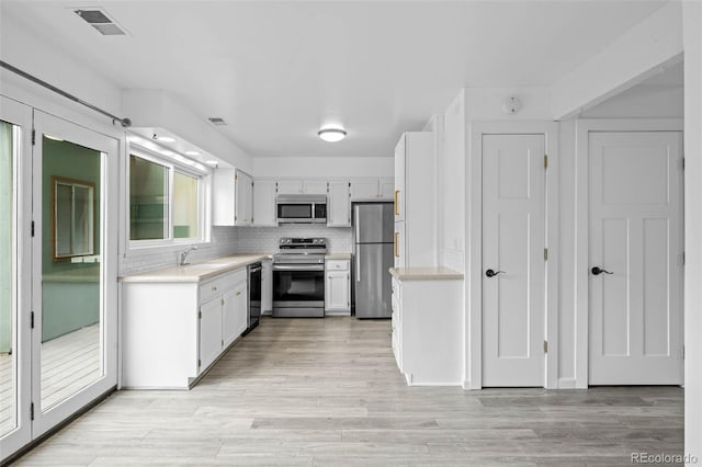 kitchen with light wood-type flooring, light countertops, appliances with stainless steel finishes, and visible vents
