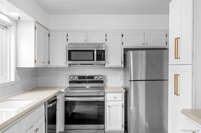 kitchen featuring a sink, appliances with stainless steel finishes, backsplash, and white cabinetry