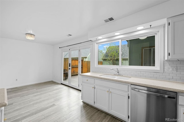 kitchen with stainless steel dishwasher, visible vents, decorative backsplash, and a sink