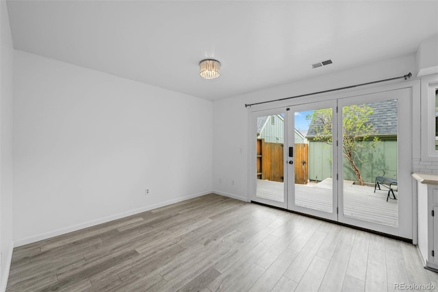 empty room with baseboards, french doors, light wood finished floors, and visible vents