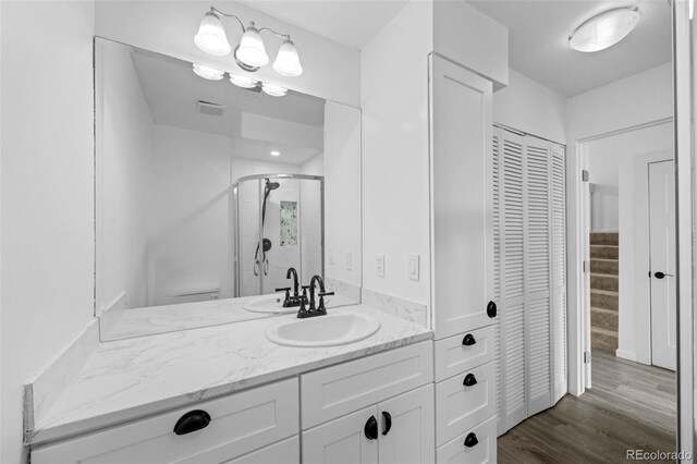 full bath featuring vanity, a shower stall, wood finished floors, visible vents, and a closet