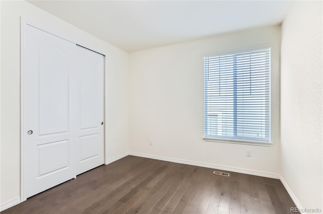 unfurnished bedroom with a closet and dark hardwood / wood-style flooring