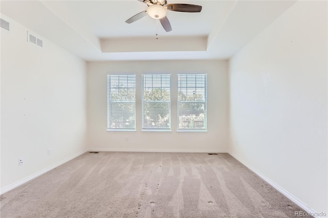 carpeted empty room featuring a tray ceiling and ceiling fan