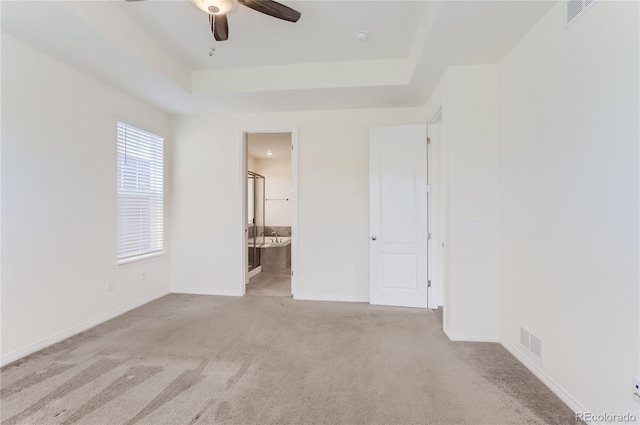 carpeted spare room featuring a tray ceiling and ceiling fan