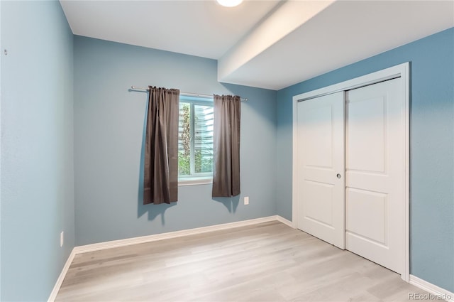 unfurnished bedroom featuring light hardwood / wood-style flooring and a closet