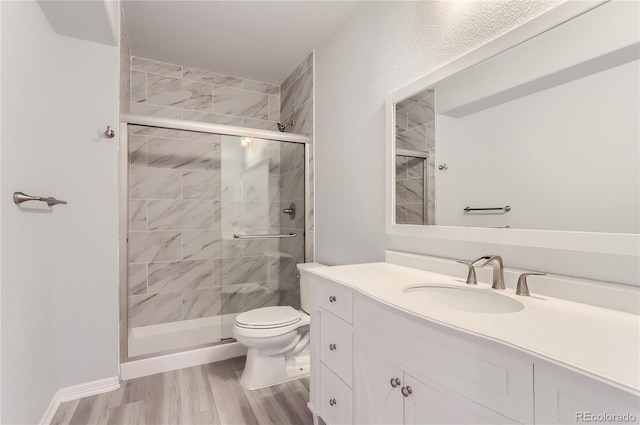 bathroom featuring vanity, hardwood / wood-style flooring, toilet, and a shower with door