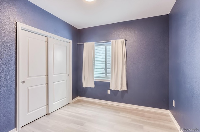 unfurnished bedroom with light wood-type flooring and a closet