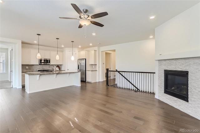 unfurnished living room featuring a fireplace, dark hardwood / wood-style flooring, ceiling fan, and sink