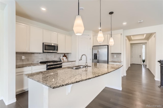 kitchen featuring white cabinets, stainless steel appliances, a kitchen island with sink, and sink