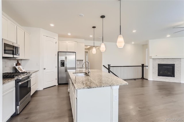 kitchen with white cabinetry, a kitchen island with sink, sink, and appliances with stainless steel finishes