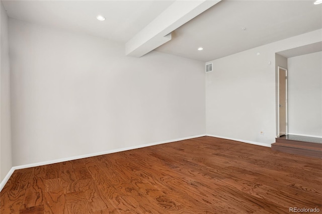 empty room featuring baseboards, visible vents, and wood finished floors