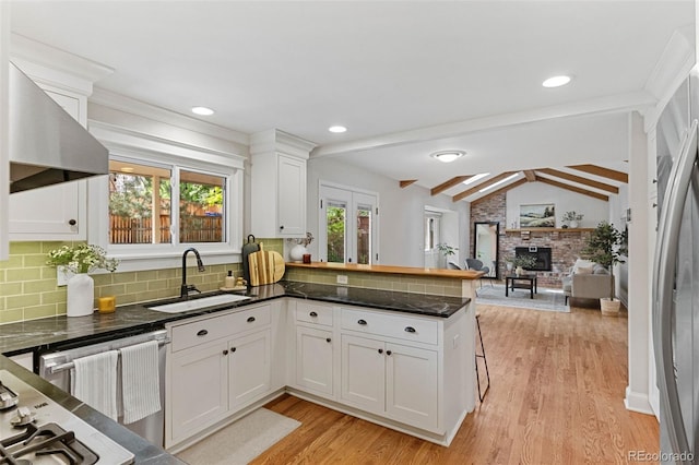 8132 Lodgepole Trl, Lone Tree, CO 80124 - kitchen with wall chimney range hood, dishwashing machine, light wood finished floors, white cabinets, and a peninsula