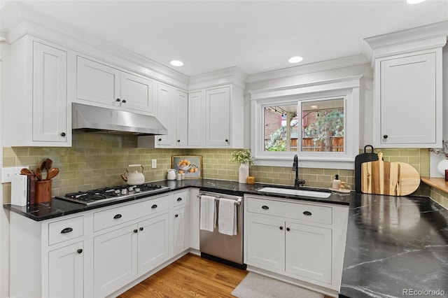 8132 Lodgepole Trl, Lone Tree, CO 80124 - kitchen with appliances with stainless steel finishes, under cabinet range hood, white cabinets, tasteful backsplash, and crown molding