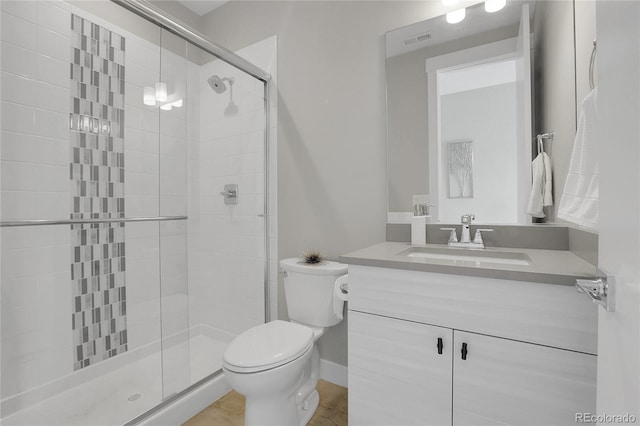 bathroom featuring vanity, a shower with shower door, and toilet