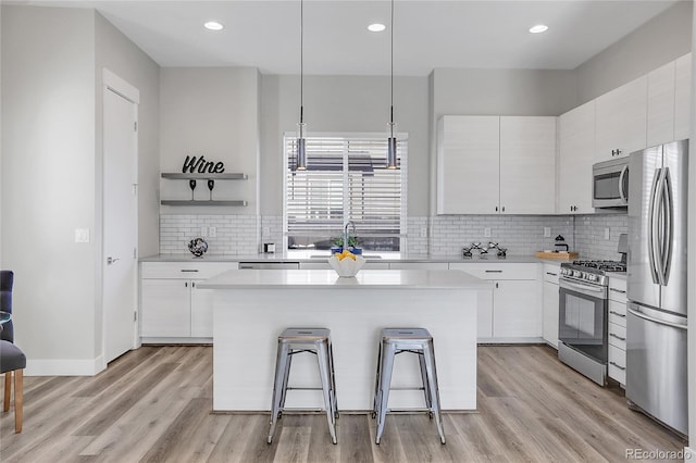 kitchen with a breakfast bar area, white cabinets, stainless steel appliances, and a kitchen island