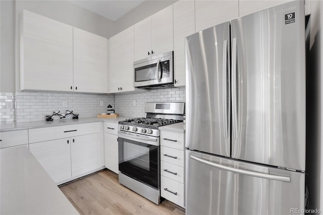 kitchen with white cabinets, light wood-type flooring, stainless steel appliances, and tasteful backsplash