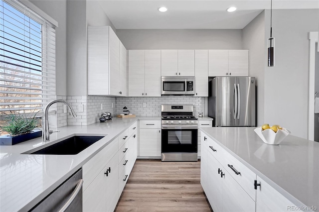 kitchen with white cabinetry, sink, pendant lighting, and appliances with stainless steel finishes