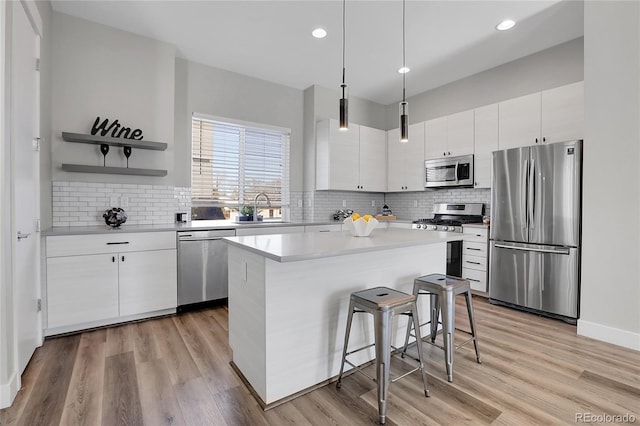 kitchen featuring appliances with stainless steel finishes, sink, pendant lighting, a center island, and white cabinetry