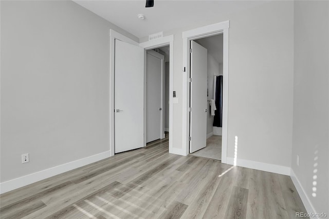 unfurnished bedroom featuring ensuite bathroom and light hardwood / wood-style flooring