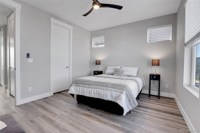 bedroom featuring ceiling fan, light hardwood / wood-style flooring, and multiple windows