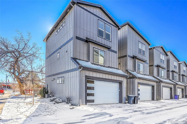 snow covered property with a garage