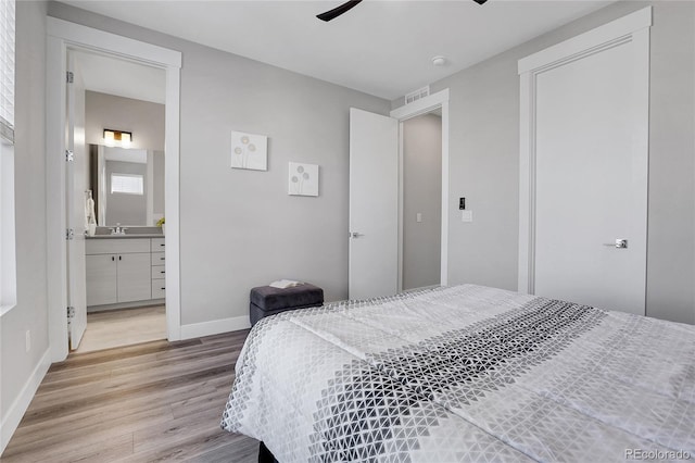 bedroom with ceiling fan, light hardwood / wood-style floors, sink, and ensuite bathroom