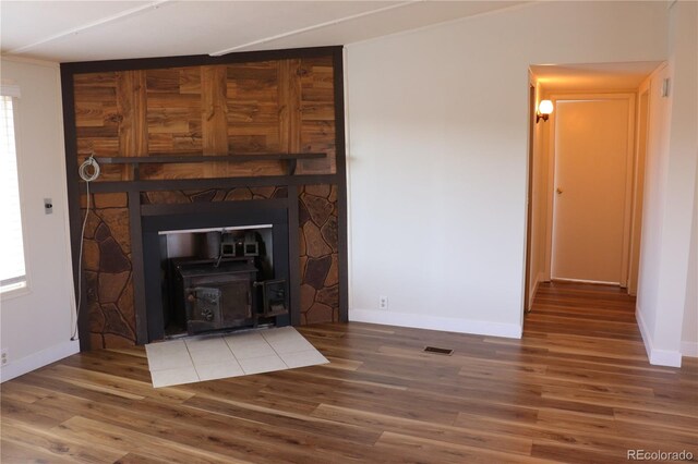 unfurnished living room featuring hardwood / wood-style floors and a wood stove