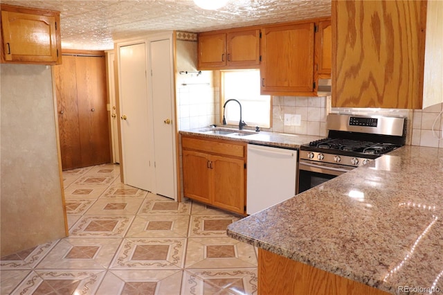 215 7th Ave, Deer Trail, CO 80105 - kitchen featuring white dishwasher, a sink, stainless steel gas range oven, light tile patterned floors, and backsplash