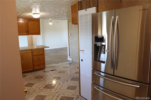 kitchen featuring ceiling fan, light stone countertops, light hardwood / wood-style floors, and stainless steel fridge with ice dispenser