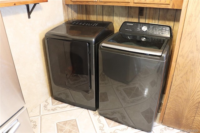 clothes washing area featuring light tile patterned floors and washer and dryer