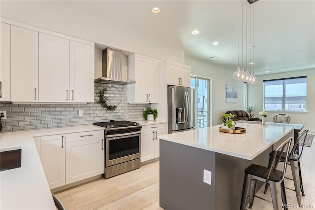 4100 E Iliff Ave Unit 4, Denver, CO 80222 - kitchen featuring stainless steel appliances, wall chimney range hood, a breakfast bar area, healthy amount of natural light, and recessed lighting