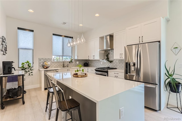 4100 E Iliff Ave Unit 4, Denver, CO 80222 - kitchen with stainless steel appliances, wall chimney range hood, light wood-style floors, decorative backsplash, and white cabinetry