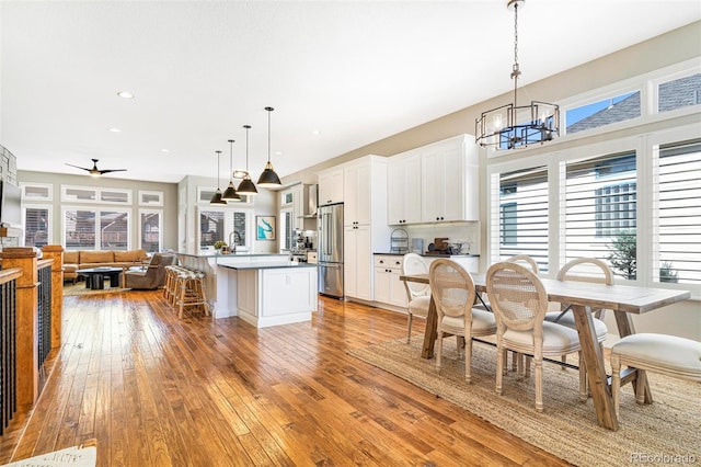 kitchen with a center island, white cabinetry, pendant lighting, high quality fridge, and light hardwood / wood-style flooring