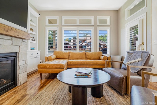 living room with built in features, light wood-type flooring, and a fireplace