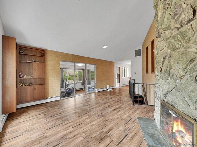 461 Nome St, Aurora, CO 80010 - living area with a baseboard heating unit, light wood finished floors, high vaulted ceiling, and a stone fireplace
