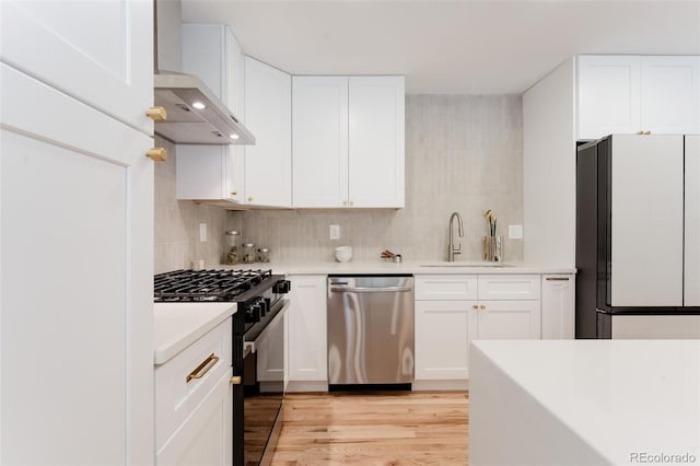 2257 S Lowell Blvd, Denver, CO 80219 - kitchen featuring freestanding refrigerator, stainless steel dishwasher, black gas range, wall chimney exhaust hood, and light countertops