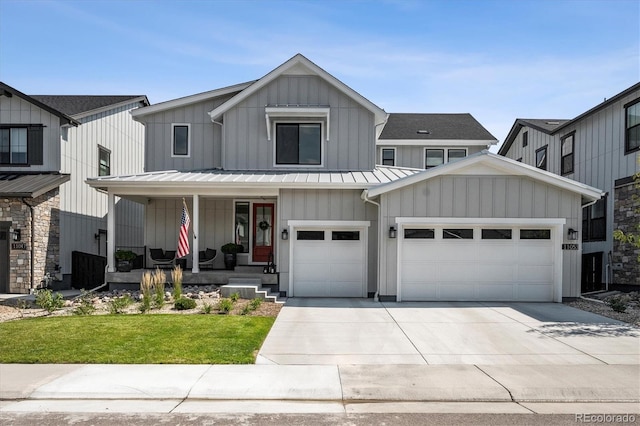 modern farmhouse with covered porch, a front yard, and a garage