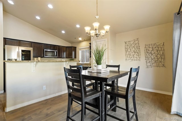 dining space featuring vaulted ceiling, wood-type flooring, and an inviting chandelier