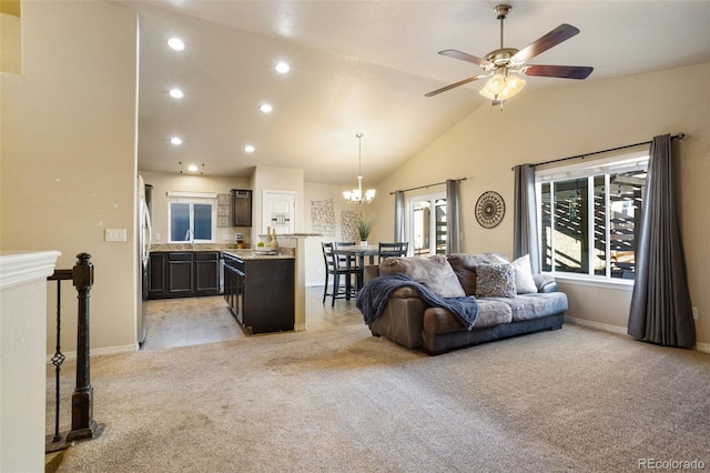 living room with ceiling fan with notable chandelier, light colored carpet, high vaulted ceiling, and sink