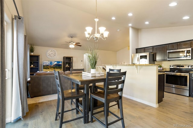 dining area featuring ceiling fan with notable chandelier, vaulted ceiling, and light wood-type flooring