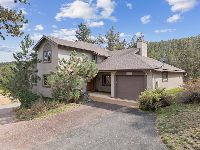 view of front of home featuring an attached garage, stucco siding, a chimney, and roof with shingles