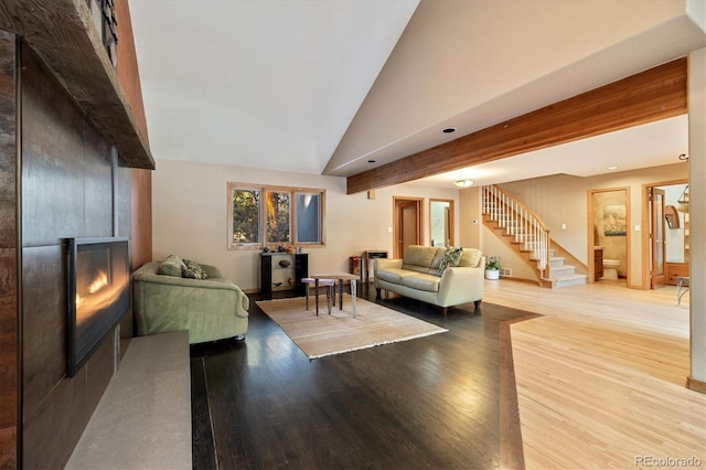 living area featuring a fireplace, stairway, wood finished floors, and beamed ceiling