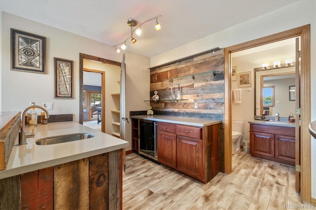 kitchen with light wood-type flooring, wine cooler, light countertops, and a sink