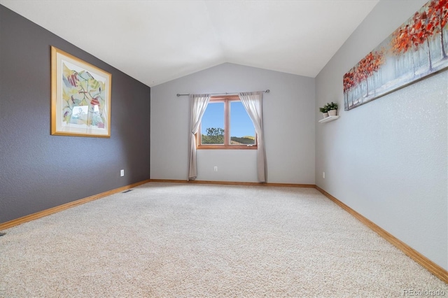 carpeted empty room with lofted ceiling and baseboards