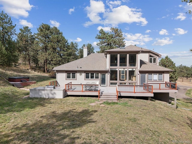 rear view of house featuring a deck, a yard, a chimney, and stucco siding