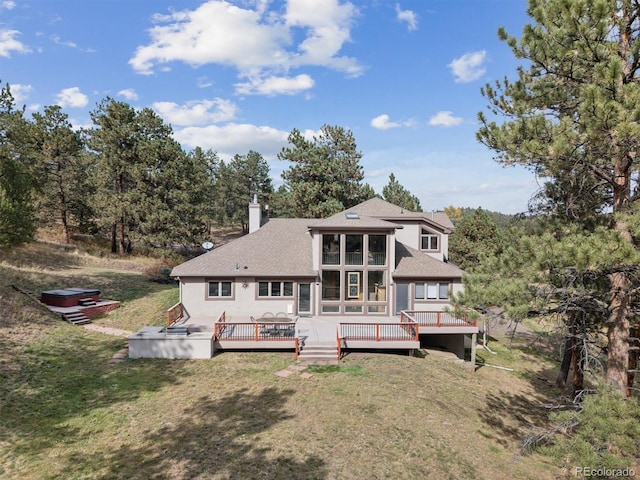 back of house featuring a shingled roof, a chimney, a deck, and a lawn