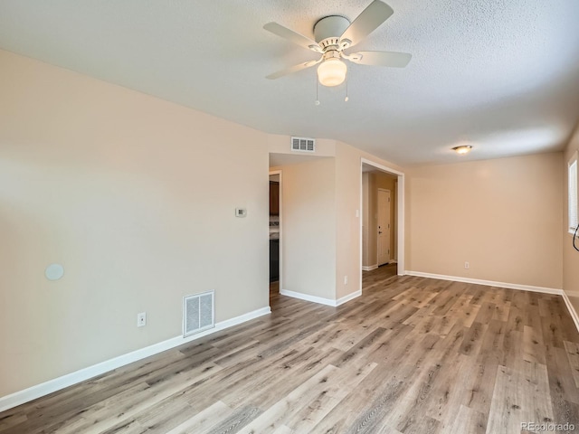 empty room with ceiling fan, light hardwood / wood-style flooring, and a textured ceiling