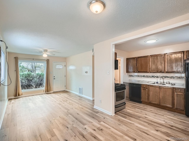 kitchen featuring light wood-type flooring, a textured ceiling, ceiling fan, sink, and black appliances